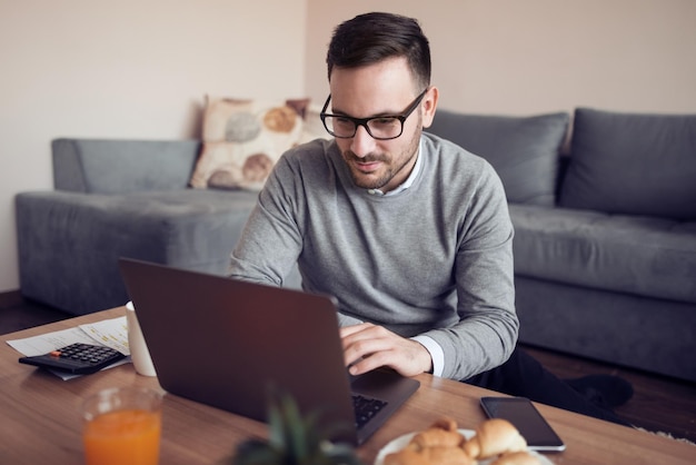 Hombre en casa trabajando en una computadora portátil