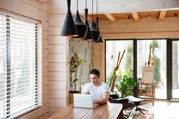 Hombre en casa usando la computadora portátil. Trabajar desde casa