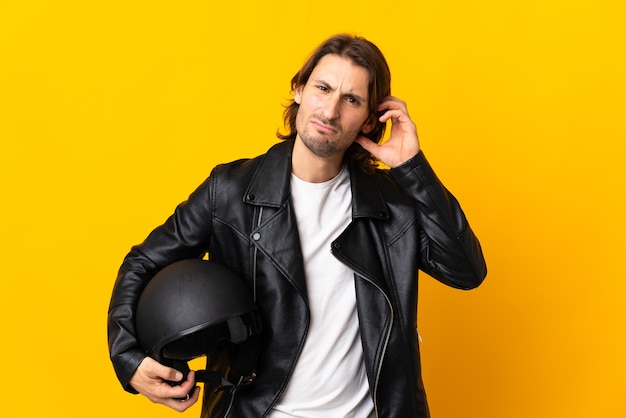 Hombre con un casco de moto aislado en amarillo con dudas