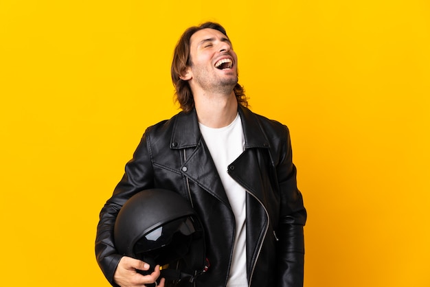 Hombre con un casco de moto aislado sobre fondo amarillo riendo