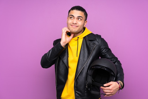 Hombre con un casco de moto aislado sobre fondo púrpura pensando en una idea