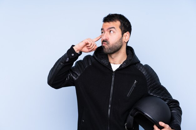 Hombre con casco de moto sobre pared aislada teniendo dudas y pensamiento