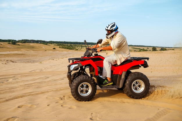 Hombre en casco paseos en atv en arenas del desierto