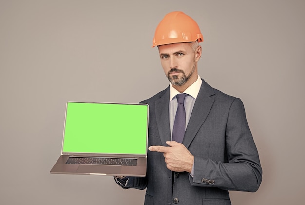 Hombre con casco señalando con el dedo en pantalla verde moderno anuncio de portátil inalámbrico