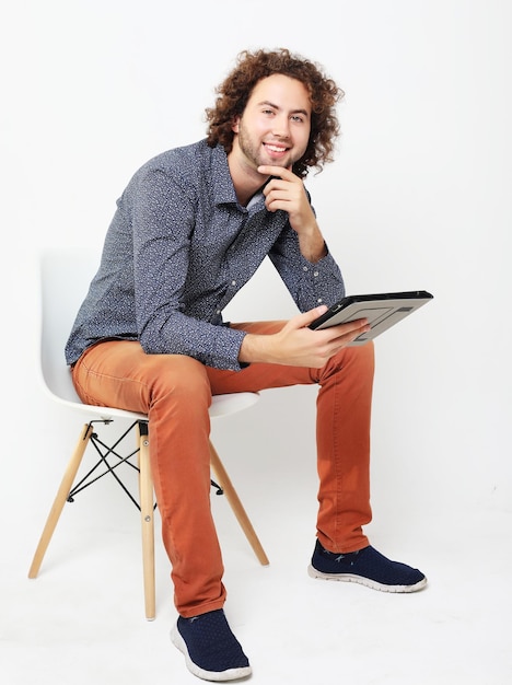 Hombre casual feliz en una silla con una tableta