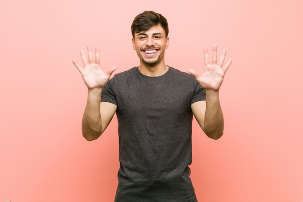 Hombre casual hispánico joven que muestra el número diez con las manos.