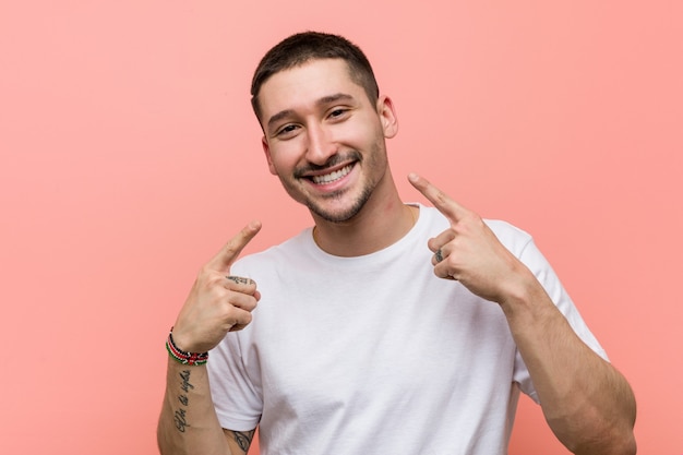 El hombre casual joven sonríe, señalando con el dedo la boca.