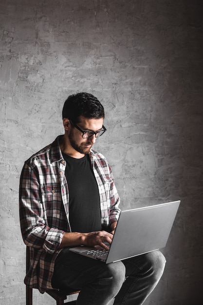 Hombre casual con portátil sobre fondo gris. internet, educación, trabajo, ocio