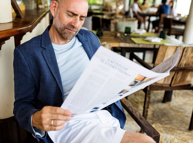 Foto hombre casual que lee un periódico en un restaurante