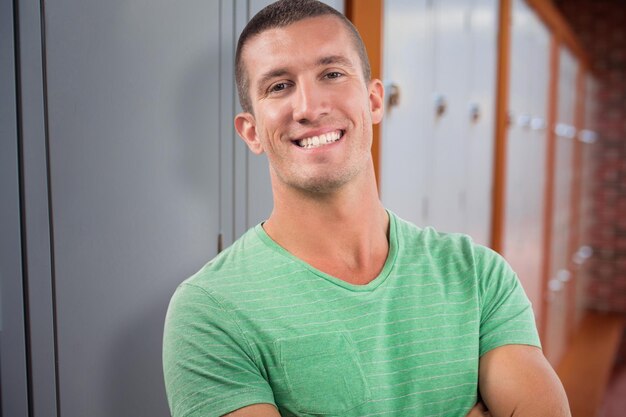 Foto hombre casual sonriendo a la cámara contra casilleros cerrados seguidos en la universidad