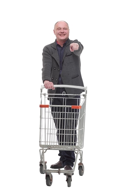 Hombre casual sonriente con carrito de compras aislado en un fondo blanco