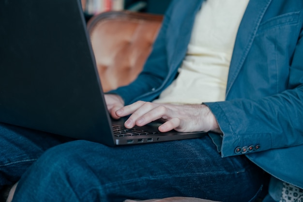 El hombre en casual trabajando en la computadora portátil, de cerca