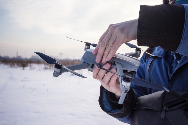 Hombre caucásico de 30 años volando Drone en campo nevado en invierno.