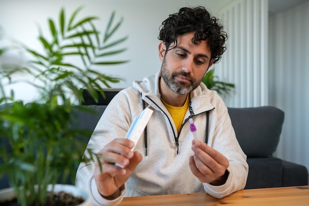 Hombre caucásico abriendo la prueba nasal rápida de antígeno COVID19 express en una mesa de madera