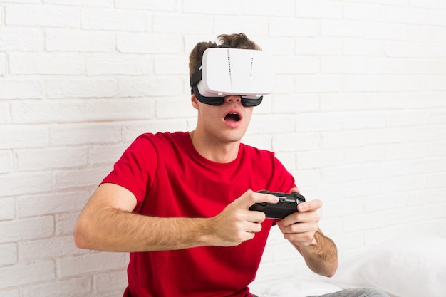 Hombre caucásico adolescente con gafas de realidad virtual y controlador de juego