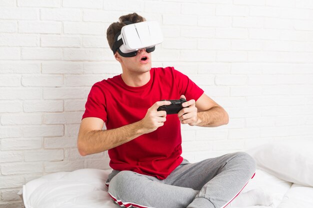 Hombre caucásico adolescente con gafas de realidad virtual y controlador de juego