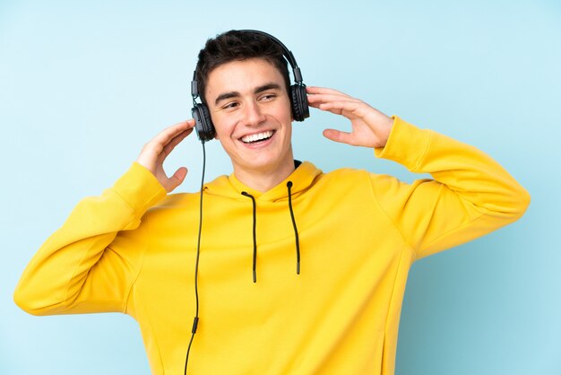 Hombre caucásico adolescente en pared púrpura escuchando música y cantando