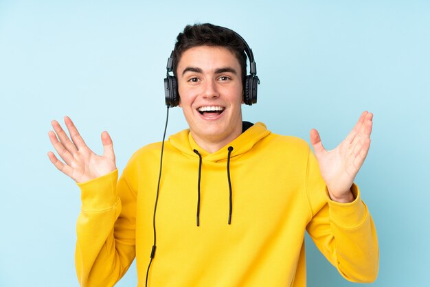 Hombre caucásico adolescente en pared púrpura sorprendido y escuchando música