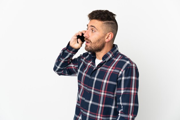 Foto hombre caucásico aislado en blanco manteniendo una conversación con el teléfono móvil