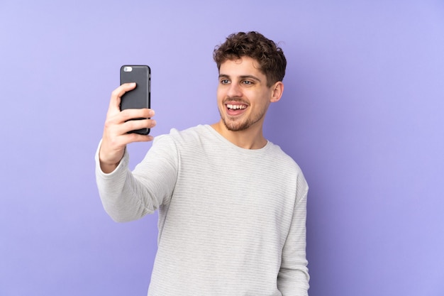 Hombre caucásico aislado en púrpura haciendo un selfie