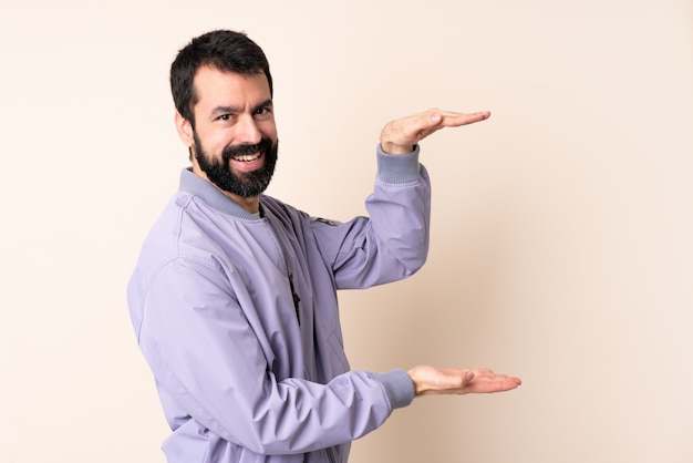 Hombre caucásico con barba con una chaqueta sobre la pared con espacio en blanco