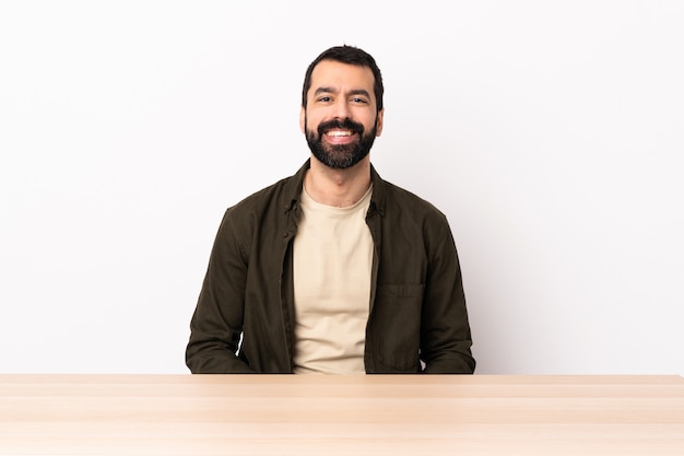 Hombre caucásico con barba en una mesa riendo