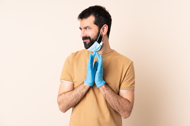 Hombre caucásico con barba protegiendo con una máscara y guantes sobre la pared intrigando algo