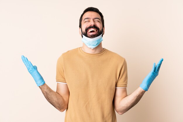 Hombre caucásico con barba protegiendo con una máscara y guantes sobre la pared sonriendo mucho