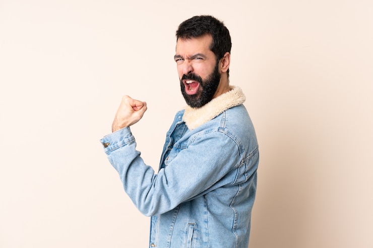 Foto hombre caucásico con barba sobre antecedentes aislados celebrando una victoria