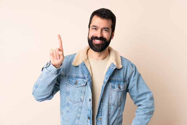 Hombre caucásico con barba sobre espacio aislado mostrando y levantando un dedo en señal de lo mejor