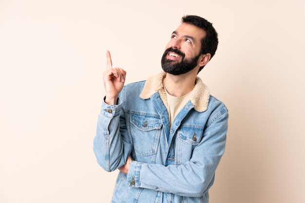 Hombre caucásico con barba sobre la pared apuntando hacia una gran idea