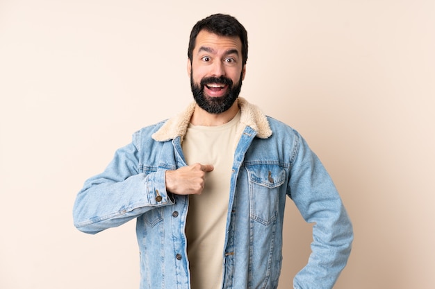 Hombre caucásico con barba sobre la pared con expresión facial sorprendida