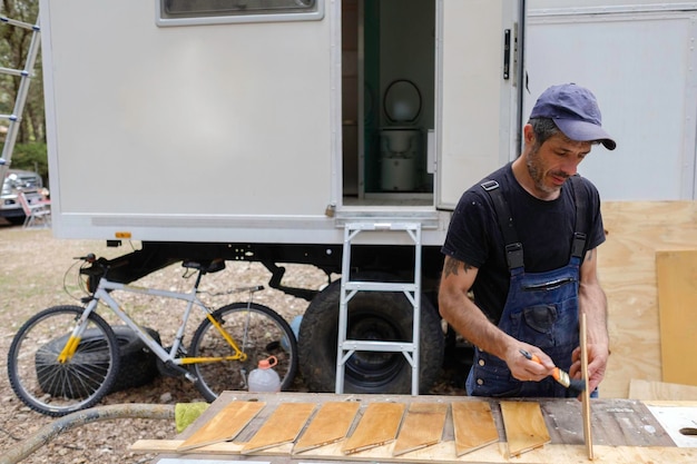 hombre caucásico blanco pintando madera para el interior de su casa rodante. Reparación de casas móviles.