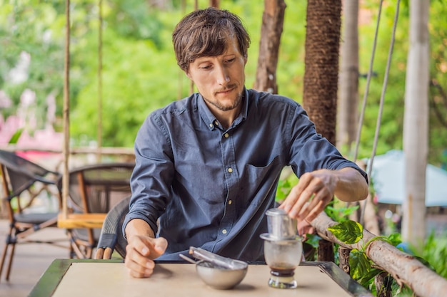 Hombre caucásico y café vietnamita elaborado por goteo tradicional a partir de un filtro phin