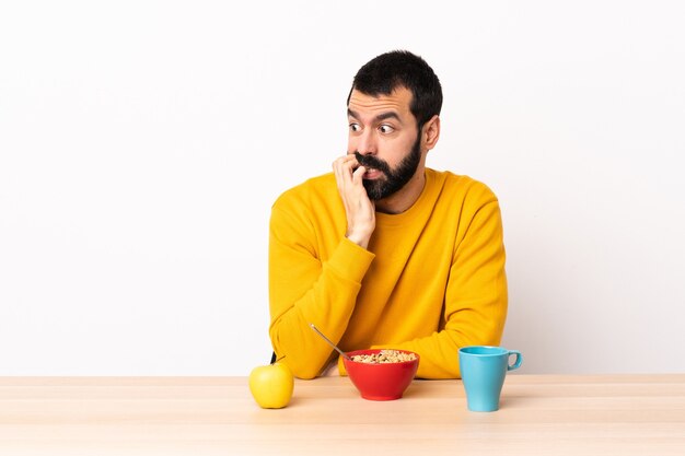 Hombre caucásico desayunando en una mesa está un poco nervioso.