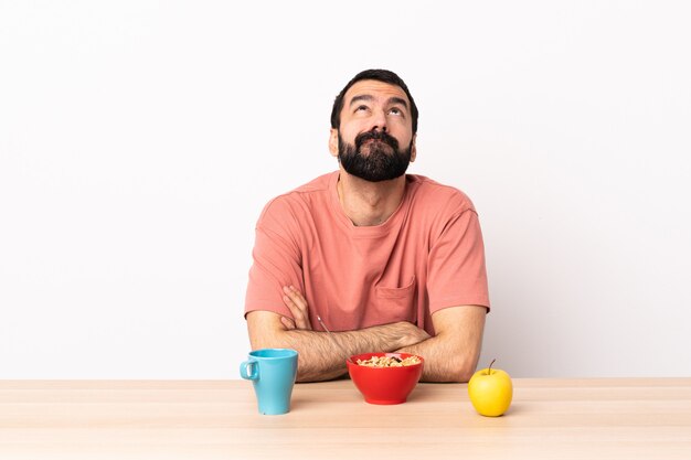 Hombre caucásico desayunando en una mesa y mirando hacia arriba