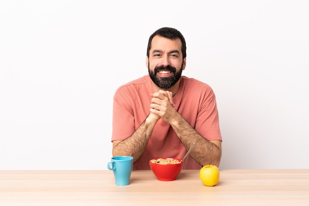 Hombre caucásico desayunando en una mesa riendo