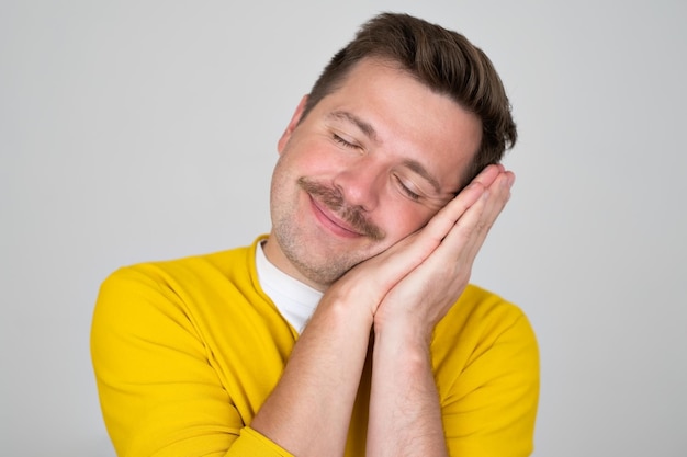 Hombre caucásico durmiendo en una almohada sonriendo descansando después de un día de trabajo