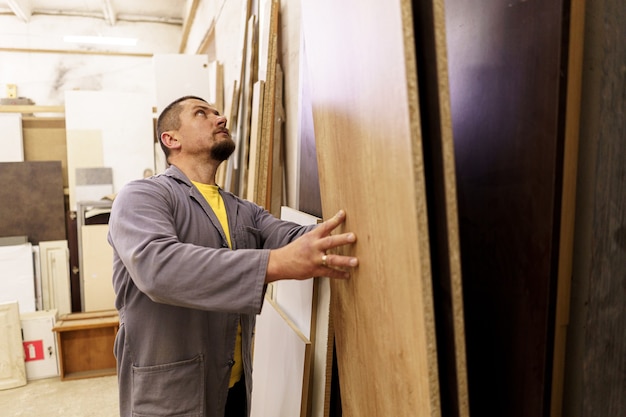Hombre caucásico elegir materiales para el diseño de muebles empotrados en su taller