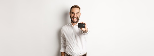 Hombre caucásico emocionado con gafas que muestran el concepto de compras con tarjeta de crédito