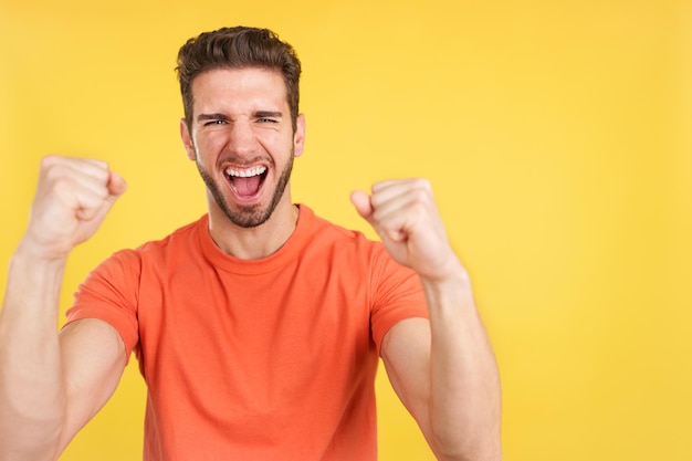 Hombre caucásico feliz celebrando mientras levanta puños