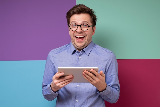 Hombre caucásico feliz en gafas con tableta digital Foto de estudio