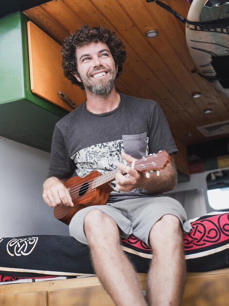 Hombre caucásico feliz tocando el ukelele en su autocaravana