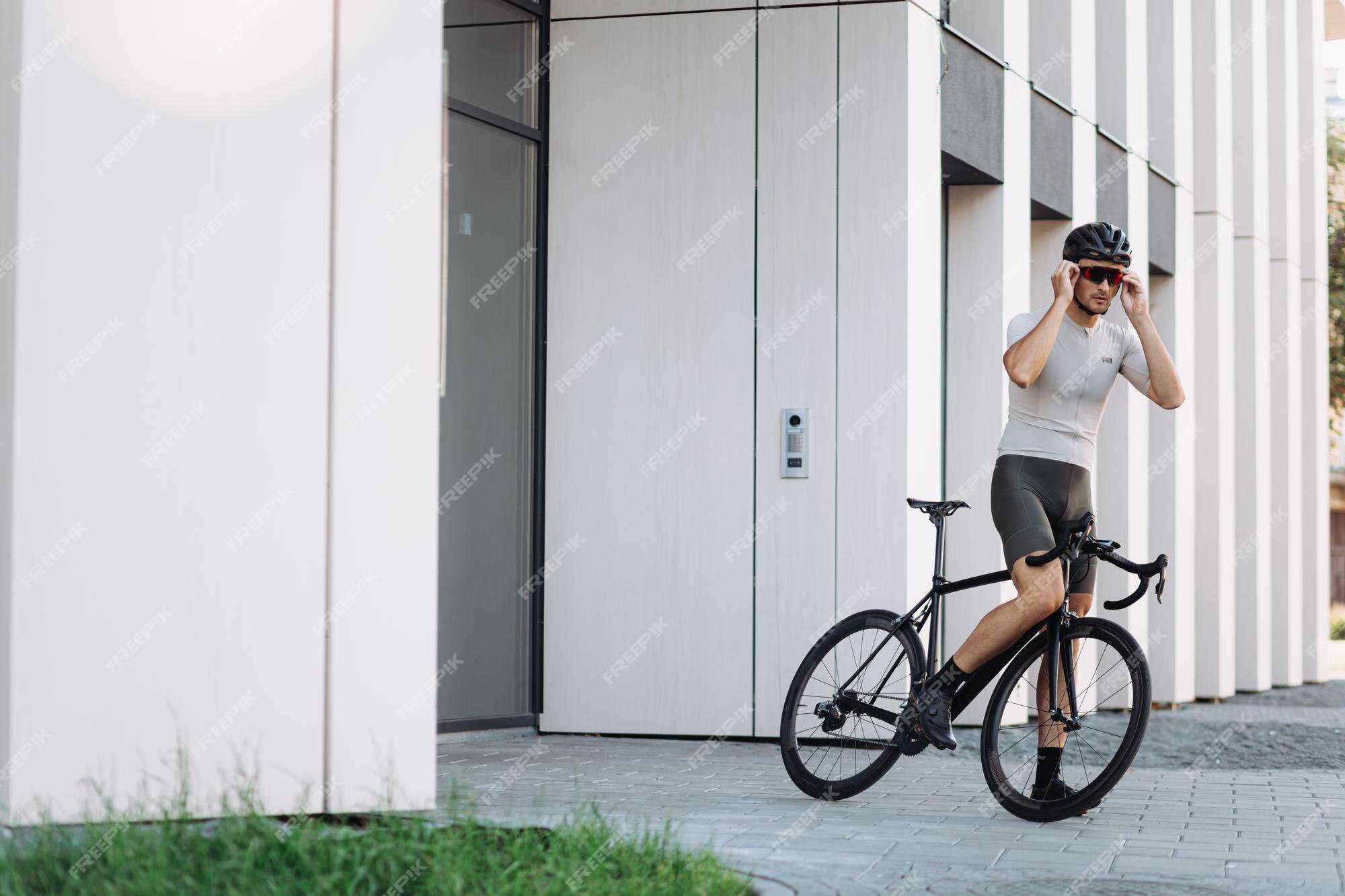 Hombre Caucásico Musculoso Con Casco De Seguridad Y Gafas Espejadas Usando  Bicicleta Negra Para Entrenar Al Aire Libre. Ciclista Pasando El Tiempo De  La Mañana Para Un Entrenamiento Intenso En La Calle