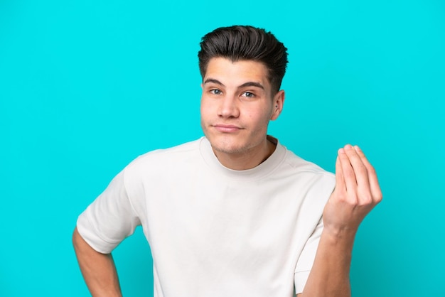 Hombre caucásico guapo joven aislado en bakcground azul haciendo gesto italiano