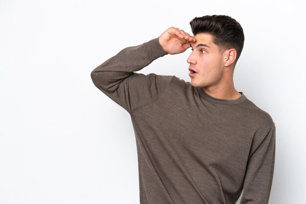 Foto hombre caucásico guapo joven aislado en bakcground blanco con expresión de sorpresa mientras mira de lado