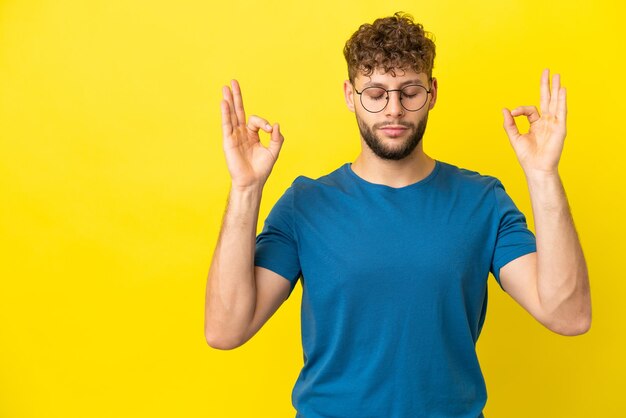 Hombre caucásico guapo joven aislado sobre fondo amarillo en pose zen