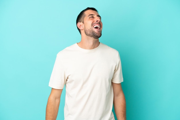 Hombre caucásico guapo joven aislado sobre fondo azul riendo