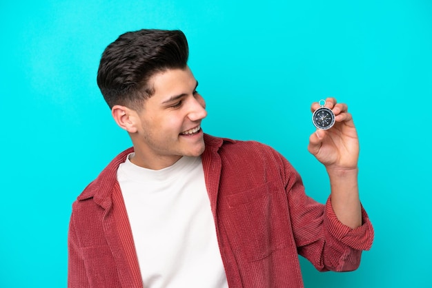 Hombre caucásico guapo joven sosteniendo brújula con expresión feliz