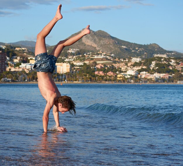 Un hombre caucásico haciendo gimnasia en una playa durante el día